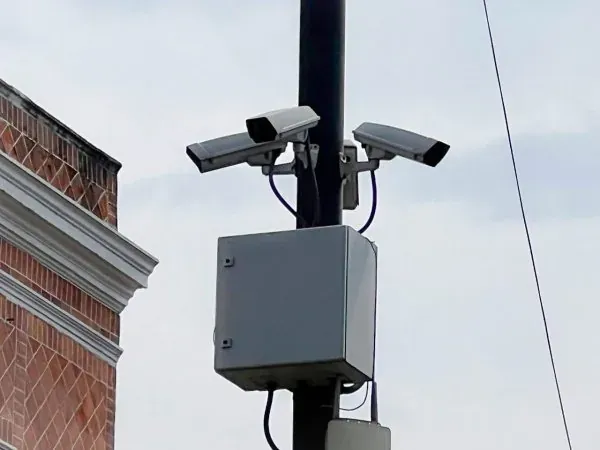 Par de cámaras fijas y gabinete de equipo montados en un poste en zona urbana